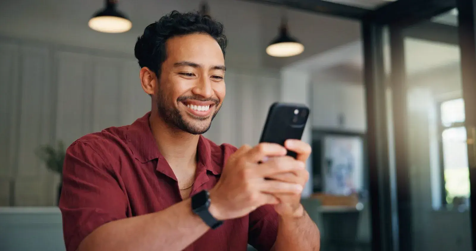 Homem sorrindo enquanto usa o celular